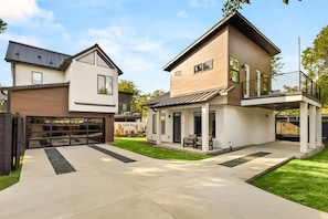 Ein modernes, zweistöckiges Haus mit Garage, überdachter Terrasse und gepflegtem Rasen.