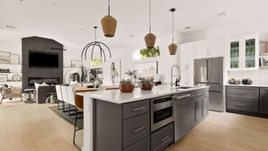 Una cocina moderna con una isla central, electrodomésticos integrados e iluminación colgante.