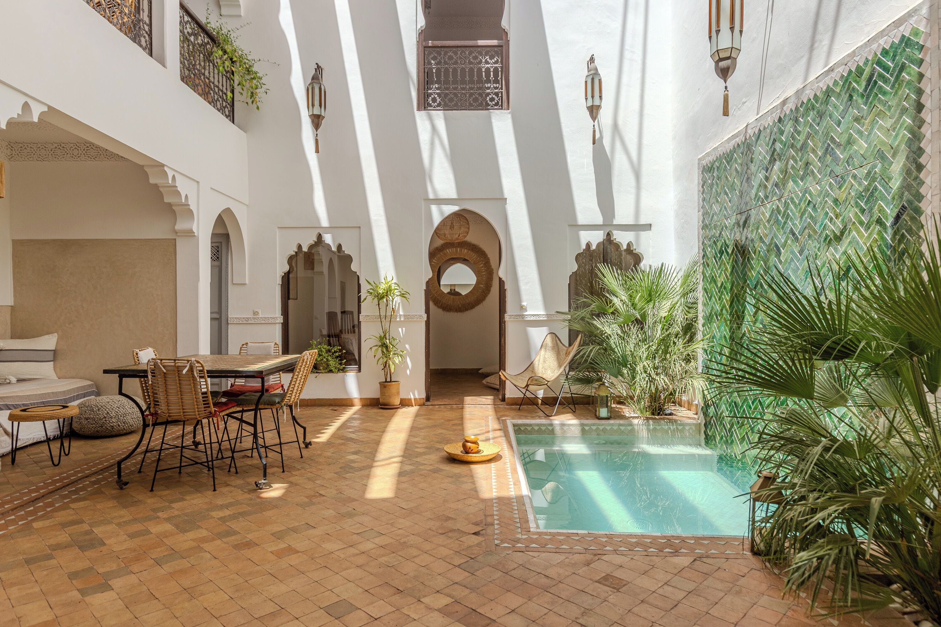A courtyard with a pool, seating area, and potted plants.