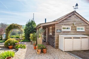 Une cabane en bois avec un porche couvert, un garage et une enseigne sur laquelle on peut lire : « La Cabane ».