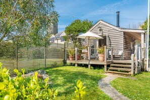 A wooden cabin with a deck, outdoor seating, and a chimney.
