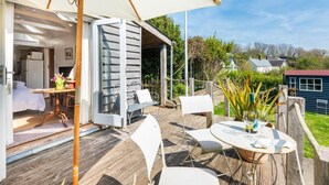Eine offene Terrasse mit Esstisch, Stühlen und einem großen Sonnenschirm.