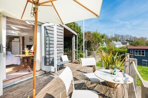 Une terrasse ouverte avec une table à manger, des chaises et un grand parasol.