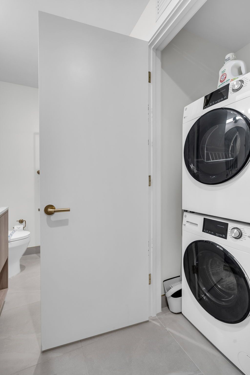 A laundry room with a white door, a washing machine, and a toilet.