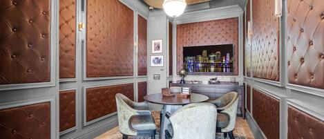 A dining area with a round table, four upholstered chairs, a cityscape view, and a decorative wall panel.