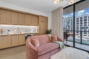 Eine moderne Küche mit Holzausstattung, einer Marmorarbeitsplatte und einer Couch im Wohnbereich.