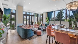 A modern hotel lobby with a curved bar, plush seating, large windows, and indoor plants. - New Designer Condo - Rooftop Pool, Spa & Views (Miami)
