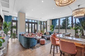 Eine moderne Hotelhalle mit einer gebogenen Bar, bequemen Sitzgelegenheiten, großen Fenstern und Zimmerpflanzen.