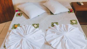 A neatly made bed with white linens and pillows, a wooden headboard, and a small bedside table with a phone. - HOTEL SOL BAHIA (Porto Seguro)