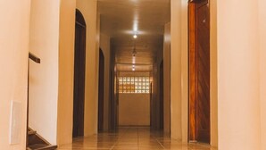 A corridor with tiled flooring, wooden doors, and a ceiling light fixture. - HOTEL SOL BAHIA (Porto Seguro)