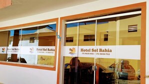 A hotel entrance with a red carpet, glass doors, and a sign reading 'Hotel Sol Bahia' with contact numbers. - HOTEL SOL BAHIA (Porto Seguro)