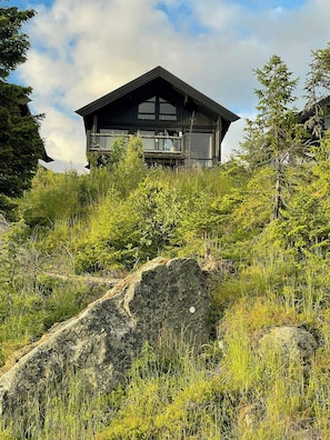 A modern mountain cabin with a balcony, surrounded by lush greenery and rocks. - Mountain cabin with panoramic view of Jotunheim (Hafjell)