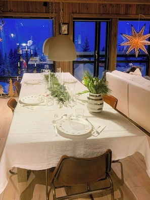 A dining table set for four with white tablecloth, candles, and a vase of greenery. - Mountain cabin with panoramic view of Jotunheim (Hafjell)