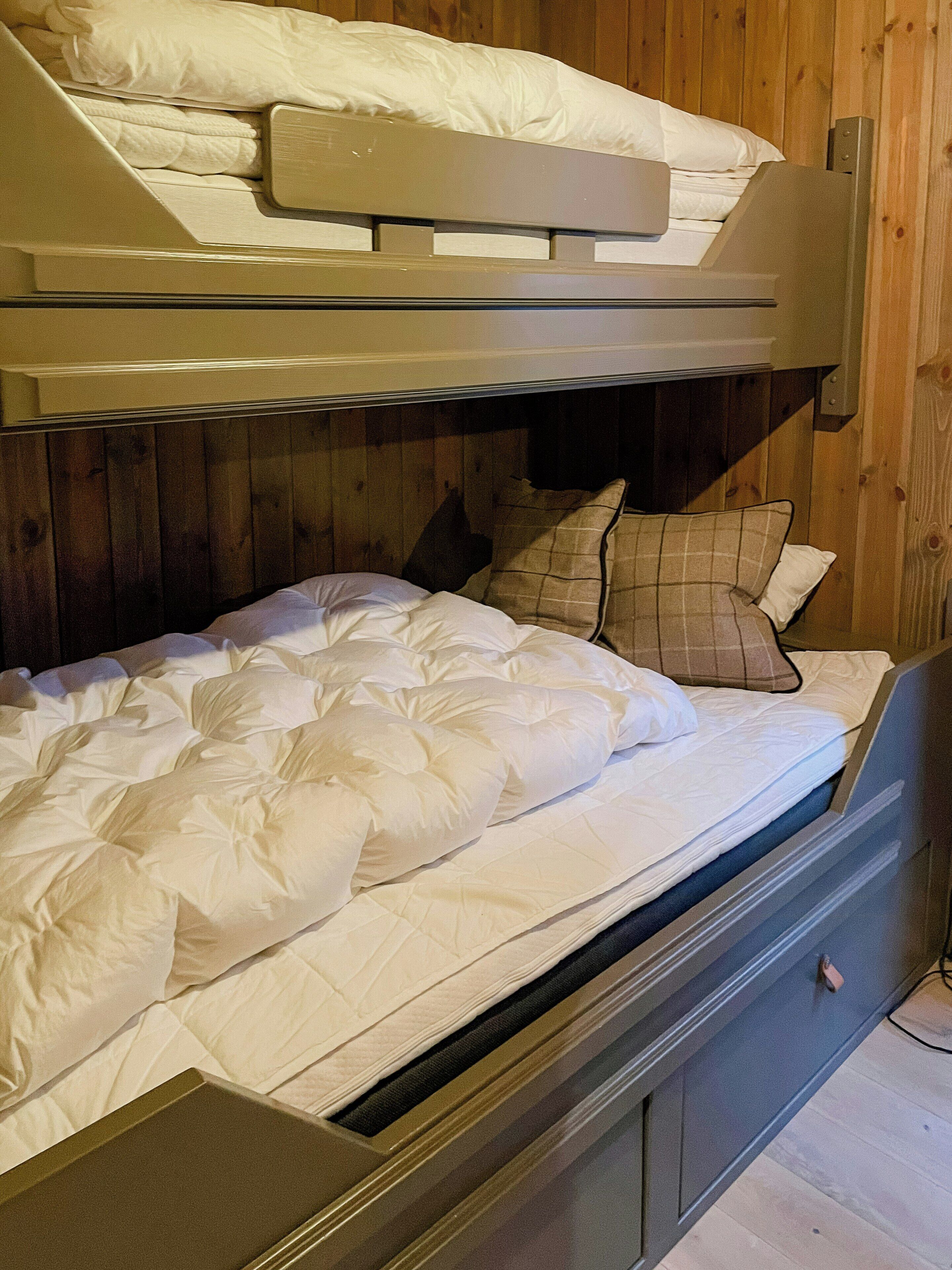 Ein Stockbett mit einer unteren Liege und einem ausklappbaren Schreibtisch.