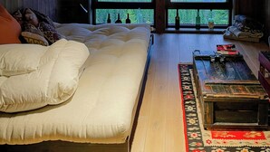 Een kamer met hoge plafonds, een groot bed, een houten vloer en uitzicht door een groot raam.