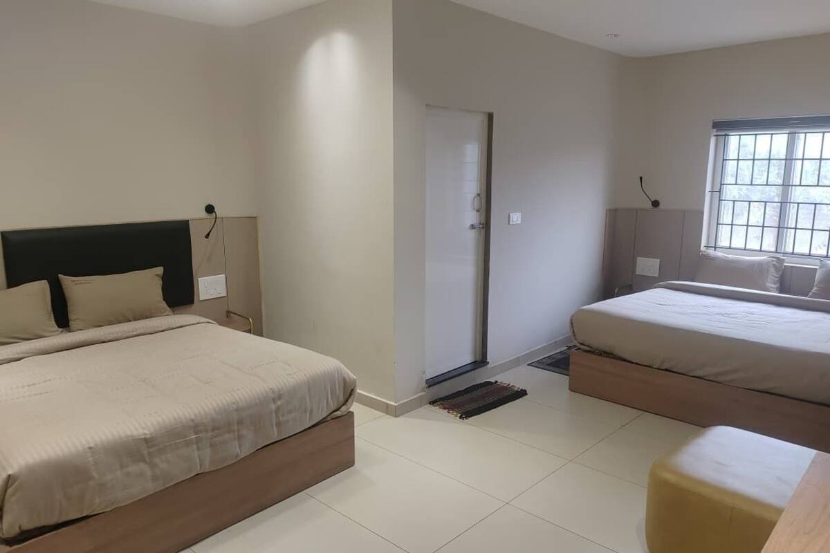 Une chambre avec deux lits, une porte, une fenêtre et une petite table.