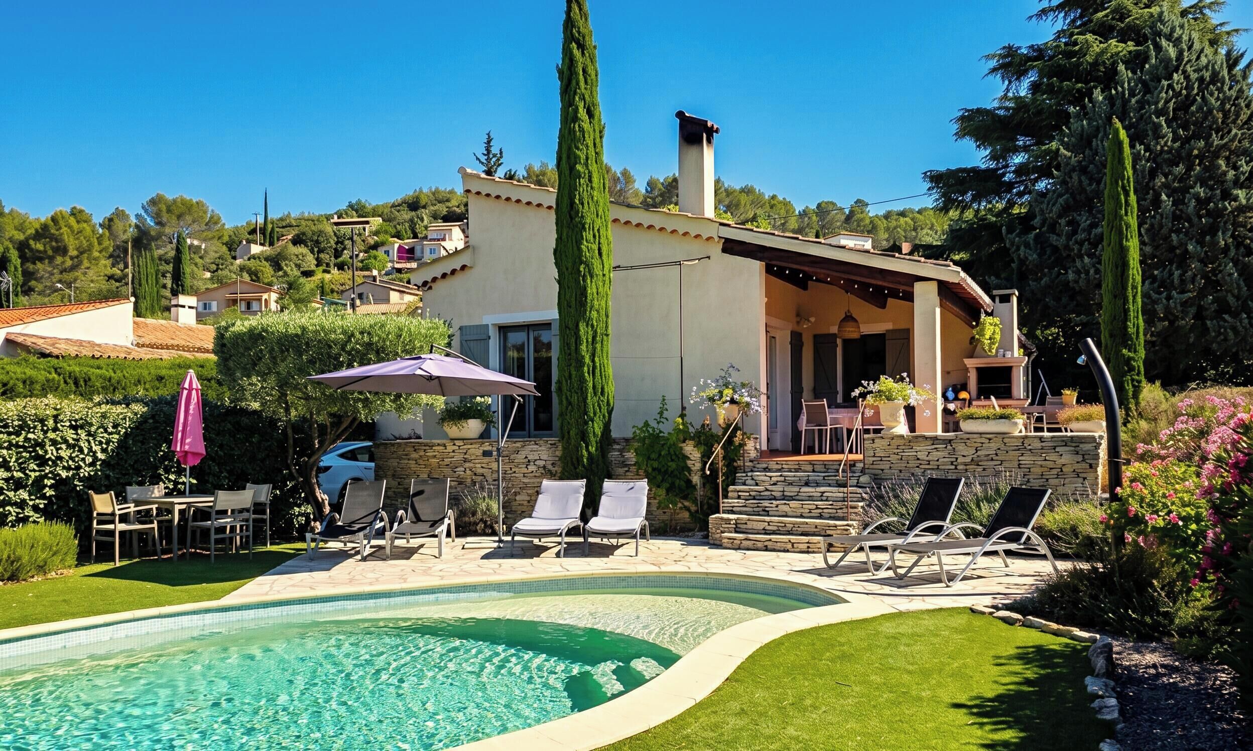 Une piscine avec des chaises longues, un mur en pierre et un bâtiment doté d’un patio couvert.