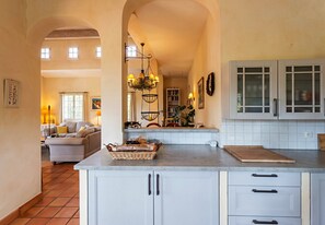 Une cuisine spacieuse avec des meubles blancs, un îlot central et un coin repas comprenant un canapé et une table.
