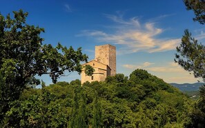 A stone church with a bell tower surrounded by dense green forest. - CASA-La Tarente villa piscine et panorama vignes (Taradeau)