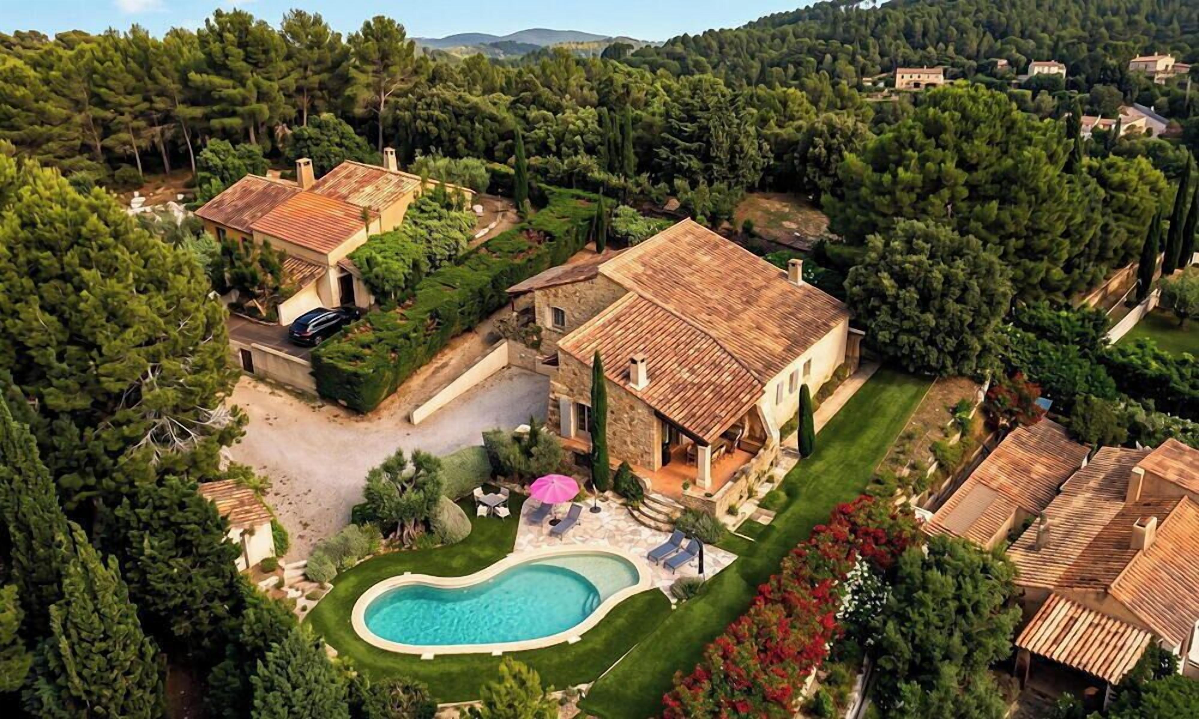 Une villa avec piscine, entourée d’une végétation luxuriante et située dans un paysage vallonné.
