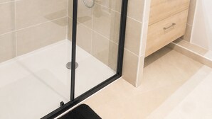 Un bagno moderno con doccia vetrata, un lavandino bianco e un mobile contenitore in legno.
