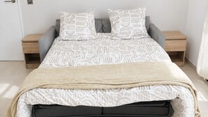 Un letto con copripiumino decorato, due cuscini, una coperta e un comodino con una lampada.
