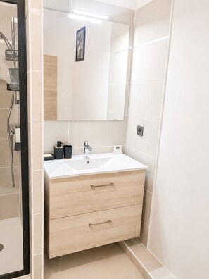 A bathroom with a white sink, a mirror, and a shower.