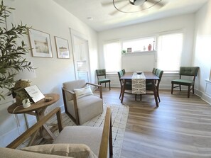 A dining area with a wooden table, green upholstered chairs, a white rug, and a plant. - Charming 3BR Home -1 Mile to Riverfront, Minutes to Louisville- Sleeps 6 (Jeffersonville)
