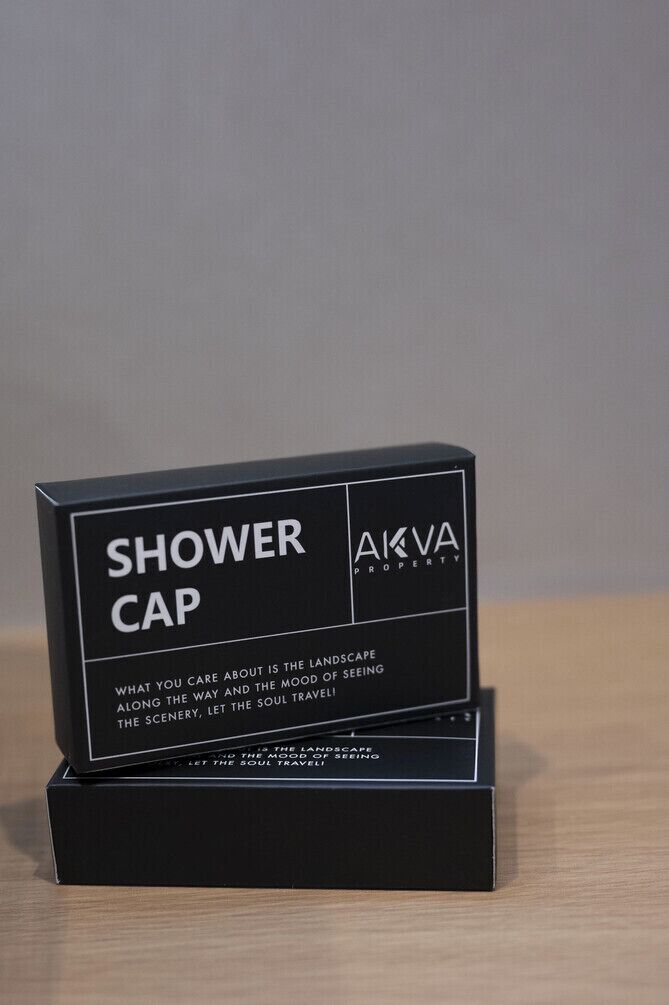A black box with 'SHOWER CAP' and 'AKVA PROPERTY' text, along with a slogan about landscape and mood.