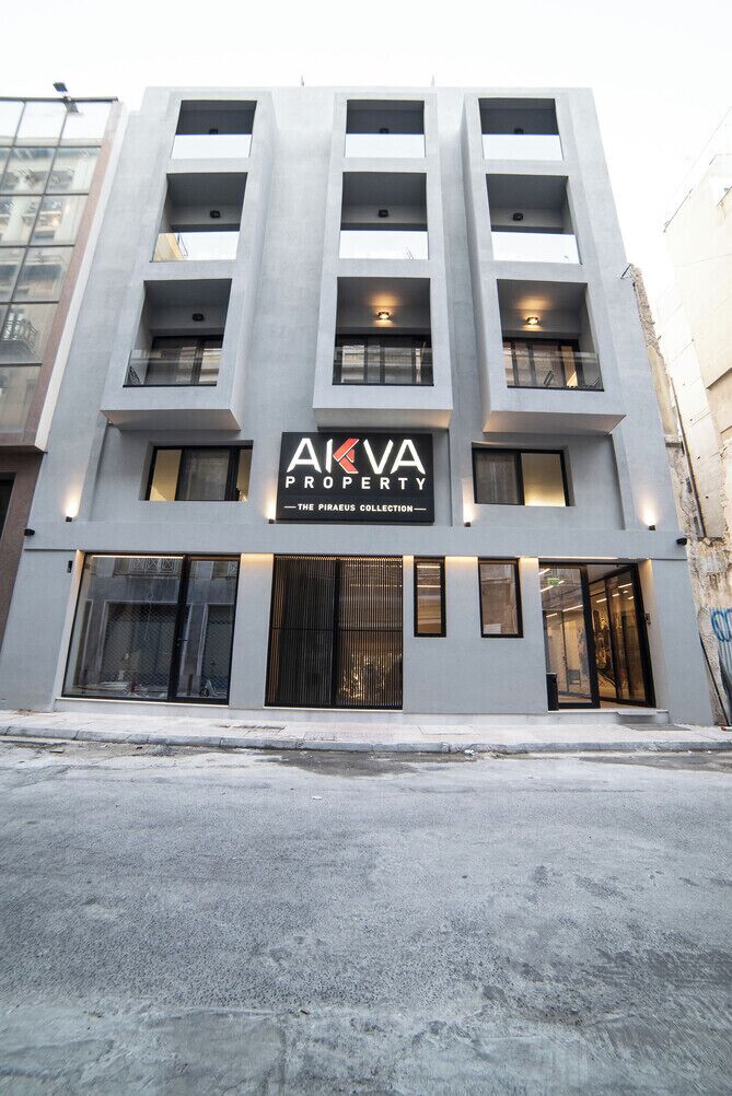Ein modernes Gebäude mit einem Schild, auf dem 'AKVA PROPERTY - THE PIRAEAUS COLLECTION' steht.