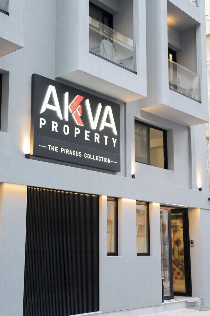Un edificio moderno con un letrero que dice 'AKVA PROPERTY - THE PIRAEUS COLLECTION'.