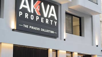 Un edificio moderno con un letrero que dice 'AKVA PROPERTY - THE PIRAEUS COLLECTION'.