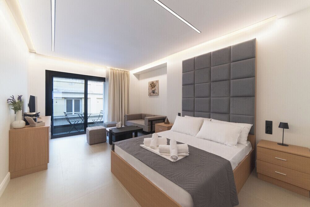 Una habitación de hotel moderna con una cama grande, un sofá, un escritorio y un balcón.