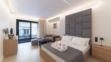 Una habitación de hotel moderna con una cama grande, un sofá, un escritorio y un balcón.