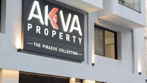 Un edificio moderno con un letrero que dice 'AKVA PROPERTY - THE PIRAEUS COLLECTION'.