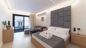 A modern hotel room with a large bed, a sofa, a desk, and a balcony. - Modern Studio in Athens. Relax, Repeat (Athens)