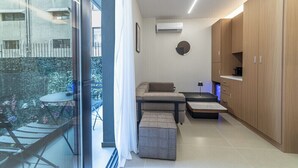 Um apartamento moderno com varanda, um sofá, uma mesinha e armários de madeira.