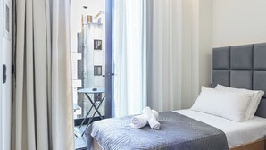 Ein Hotelzimmer mit Bett, einem kleinen Tisch und Blick nach draußen.
