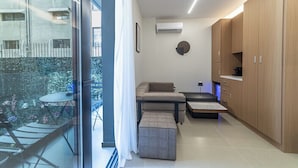 Eine moderne Wohnung mit Balkon, einer Couch, einem kleinen Tisch und Holzschränken.