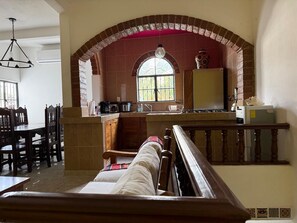A dining area with a high arched brick ceiling, a kitchen with a window, and a staircase leading to an upper level. - Modern Mexican-Style House Just Steps from the Stadium and Close to the Beach and the Boardwalk ⭐ (Puerto Vallarta)