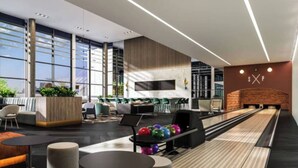 Um lounge moderno com pista de boliche, áreas de estar e bar.