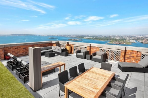An outdoor patio with seating, a table, and a view of the water.