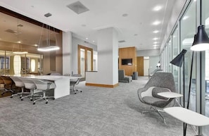 A modern office space with a conference table, office chairs, a reception desk, and a large window.