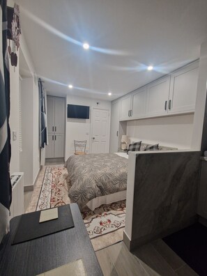 A compact bedroom with a bed, a desk, a chair, and a wardrobe.