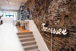 Eine Treppe führt zu einem Raum mit einer Ziegelwand und einem Schild mit der Aufschrift 'Tennessee'.
