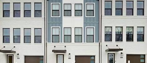 Un immeuble à plusieurs étages, doté d’une façade symétrique, de grandes fenêtres et de portes de garage.