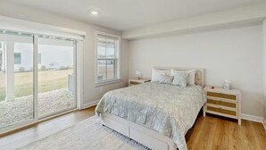 Un dormitorio con cama, mesita de noche, ventana y vistas al exterior.