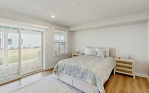 Ein Schlafzimmer mit einem Bett, einem Nachttisch, einem Fenster und Blick ins Freie.