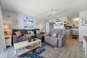 Ein Wohnzimmer mit Sofa, Sessel, Couchtisch und Dekoration.