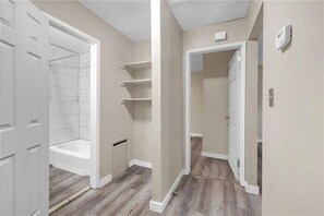 Ein Flur mit Dusche, begehbarem Kleiderschrank und einer Tür zu einem weiteren Raum.